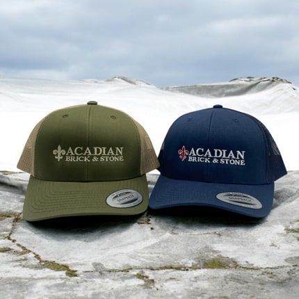 Olive green and navy trucker caps featuring the Acadian Brick & Stone logo.