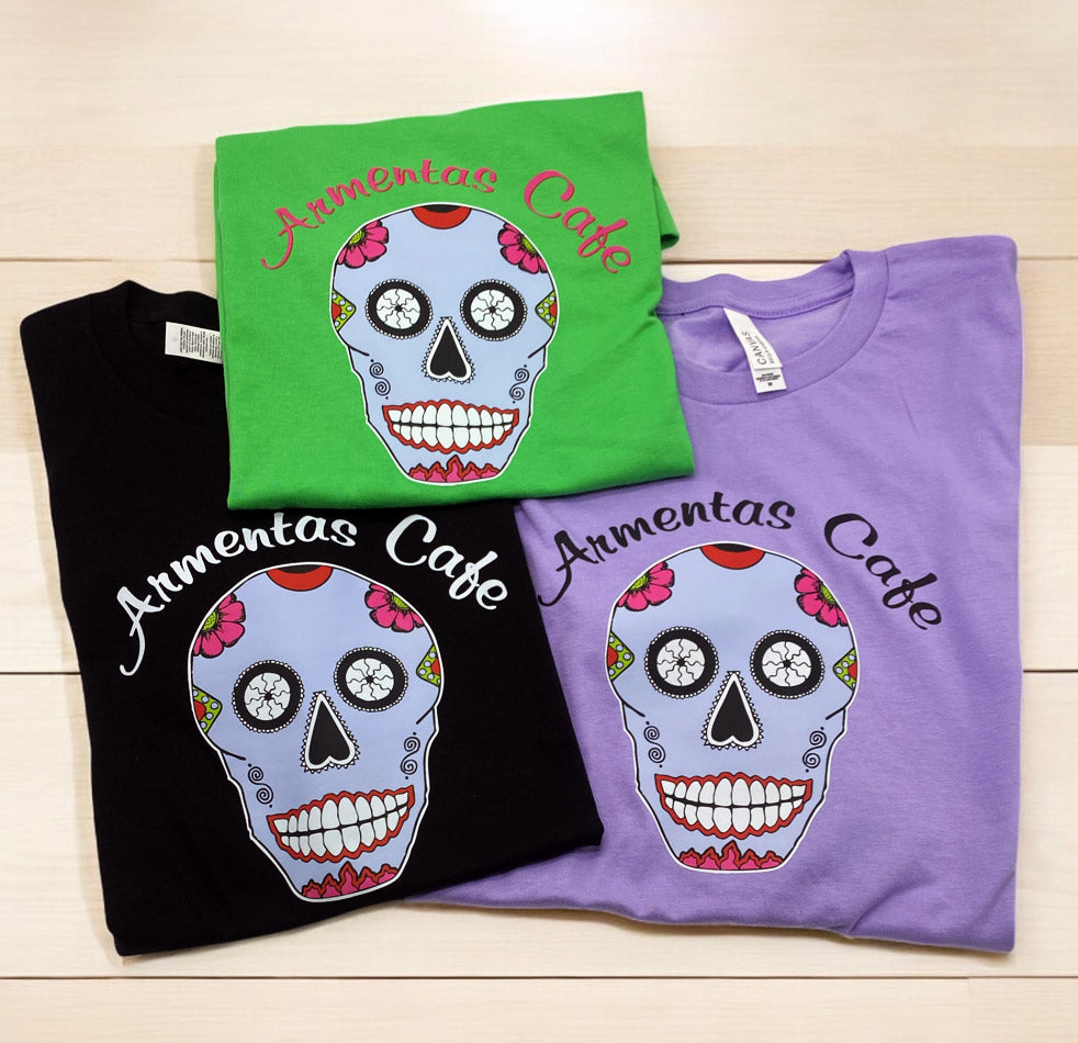 Colorful sugar skull t-shirts in green, black, and purple with Armentas Cafe logo