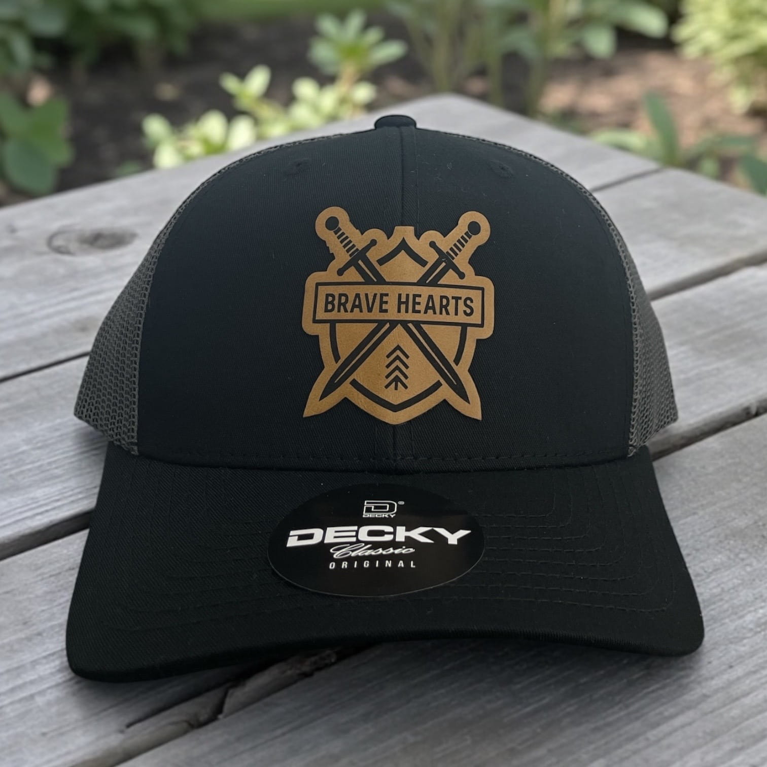 Black Decky trucker hat with tan Brave Hearts shield logo and crossed swords patch on the front.