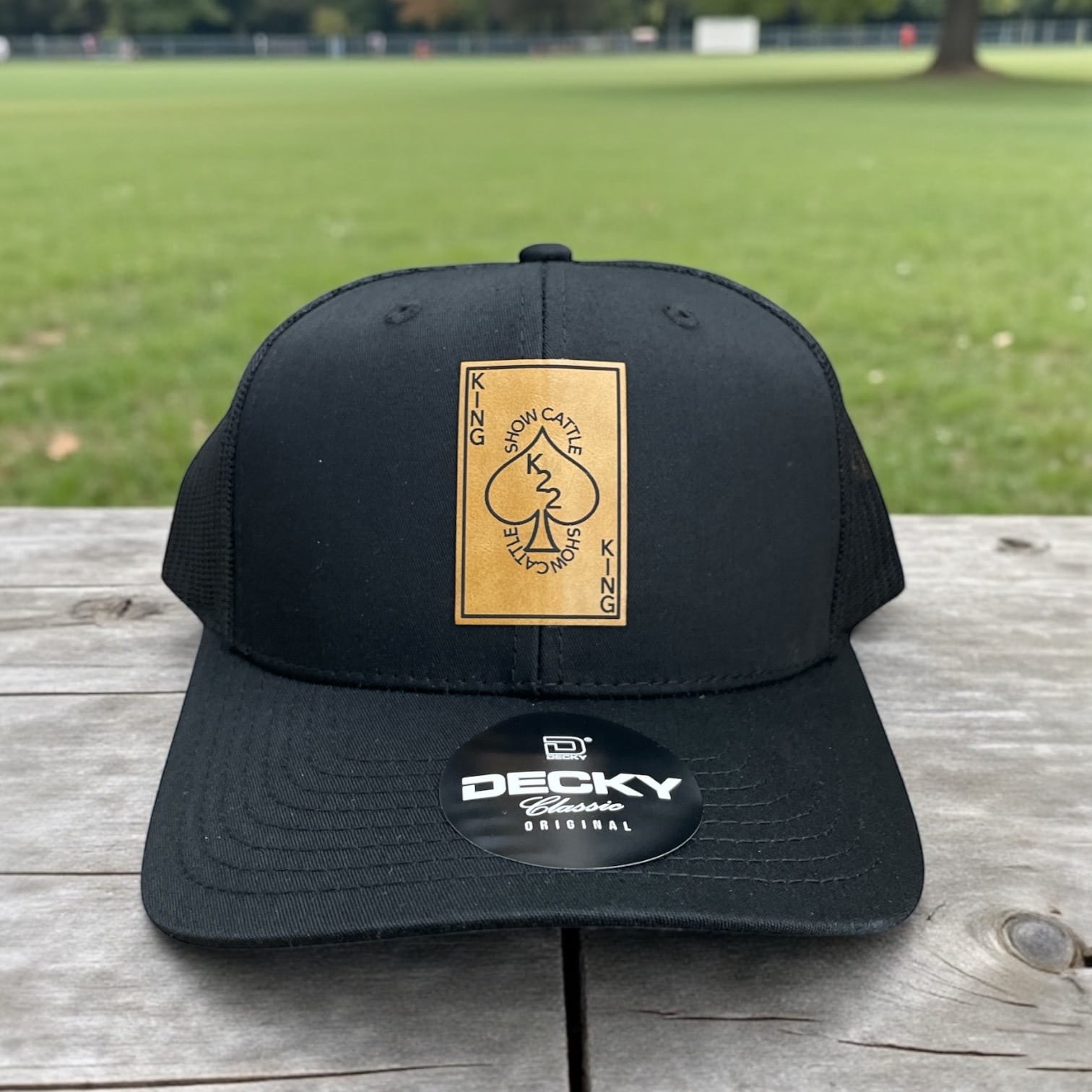Black Decky trucker hat with gold playing-card style King Show Cattle patch on the front panel.