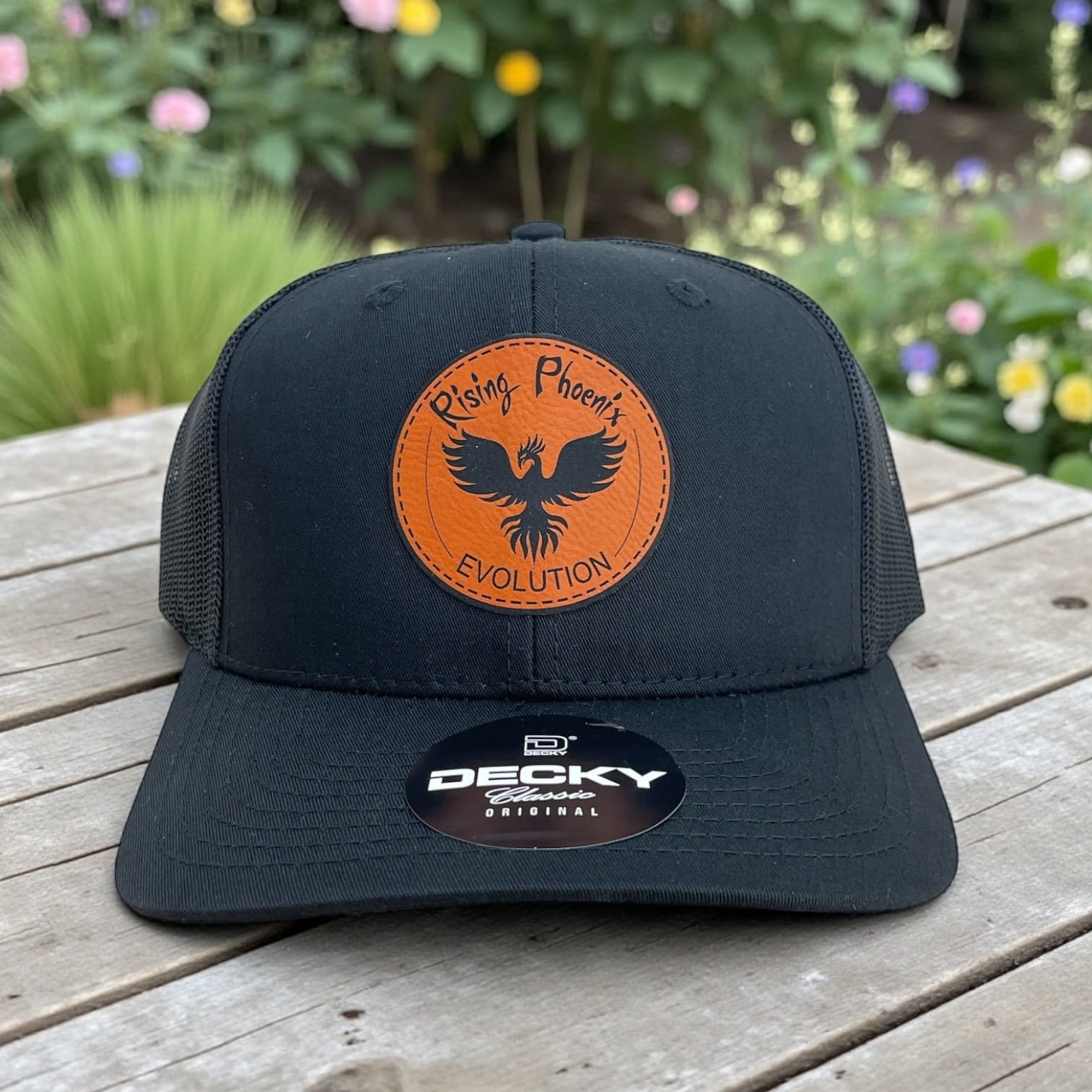 Black Decky trucker hat with orange leather Rising Phoenix Evolution patch and phoenix graphic on the front.