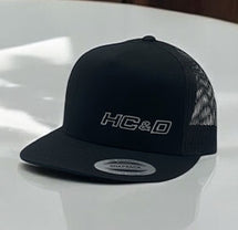 Black HC&D cap with white embroidered text logo.