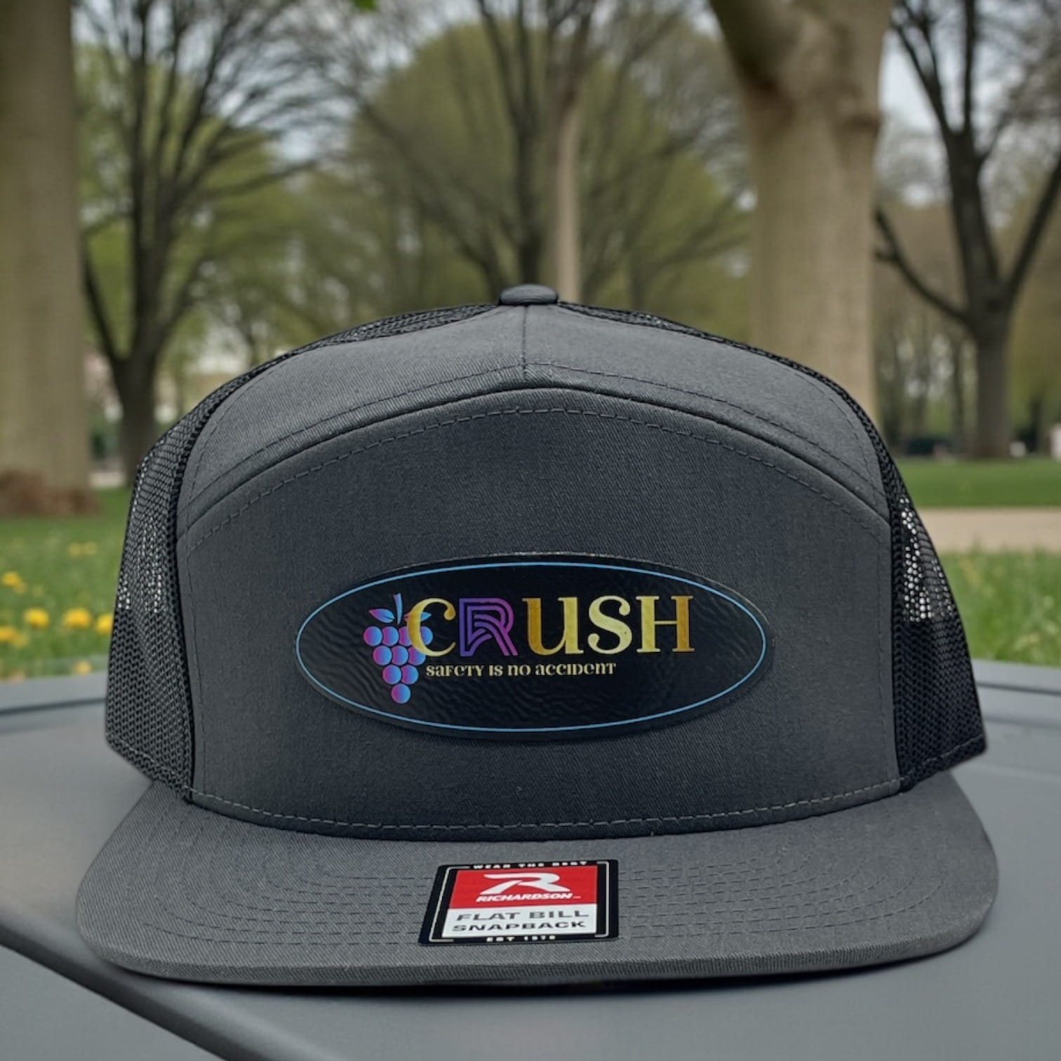 Gray and black Richardson flat bill snapback hat with CRUSH logo, grape icon, and “Safety is no accident” tagline.