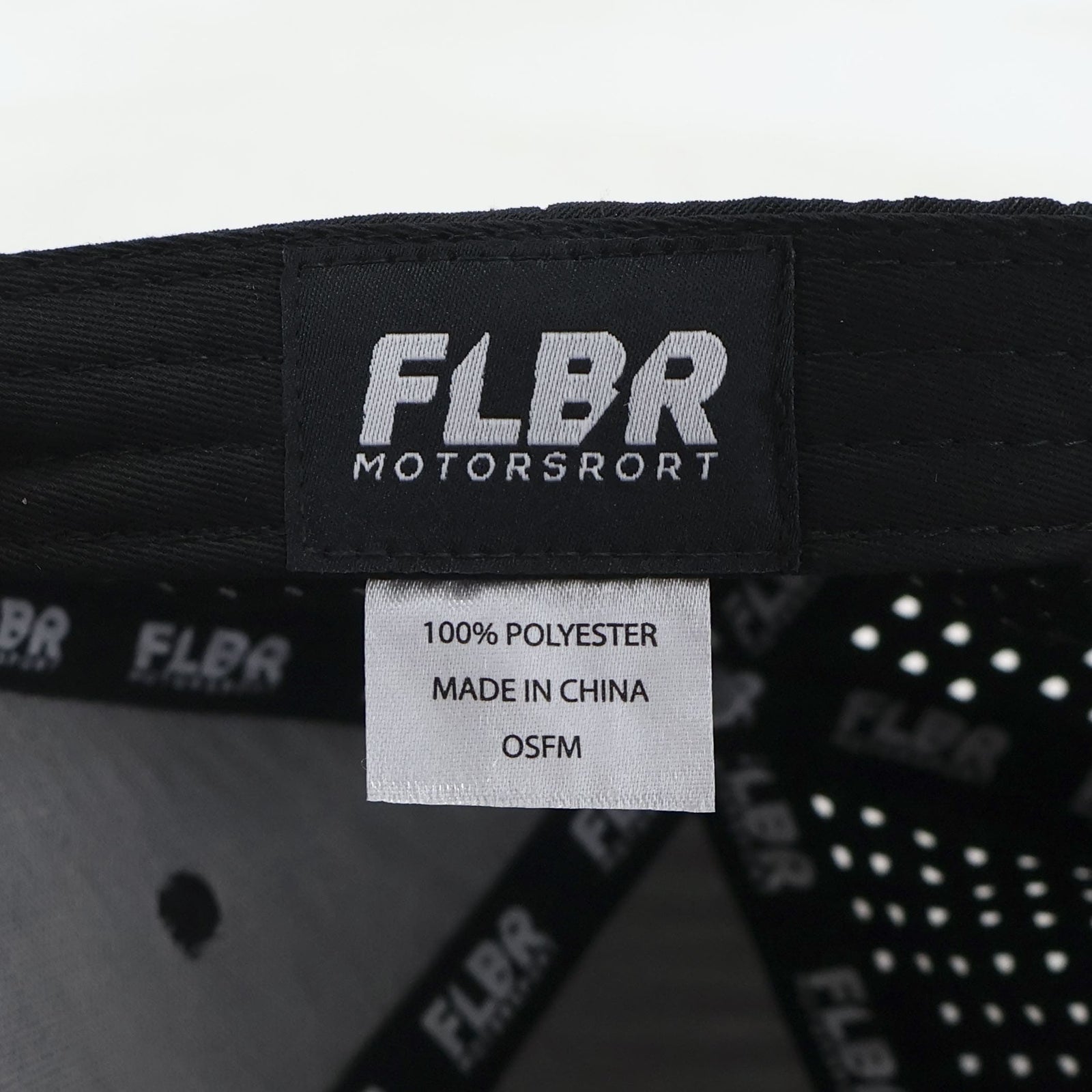 Close-up of inside label “FLBR MOTORSPORT” with care tag: 100% polyester, Made in China, OSFM.