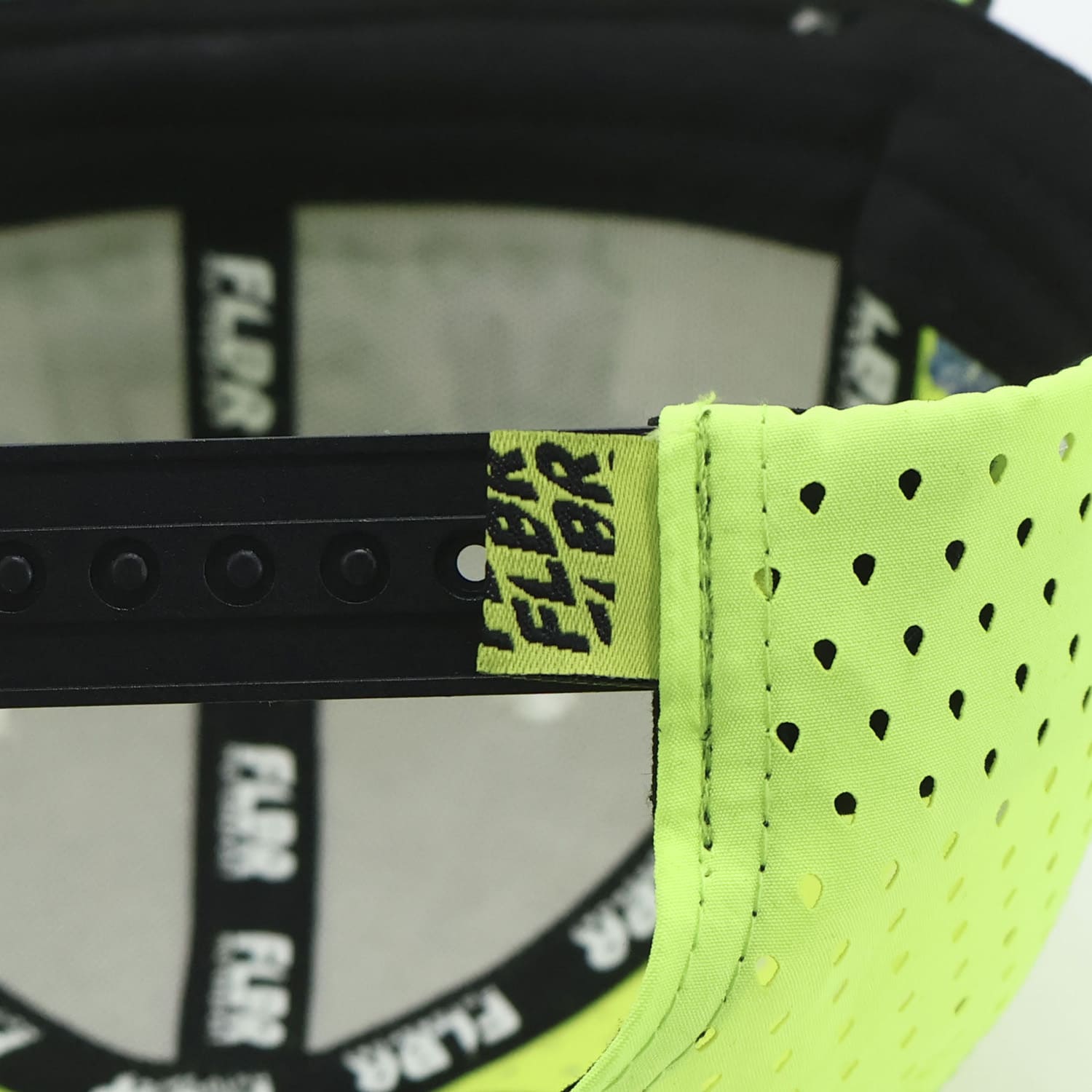 Close-up of snapback strap and neon yellow perforated fabric tab on FLBR Motorsport cap.