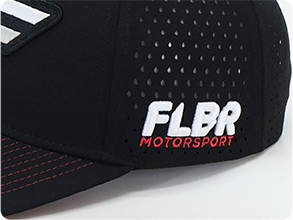 Side view of a black FLBR Motorsport baseball cap with white and red embroidered logo on perforated panel