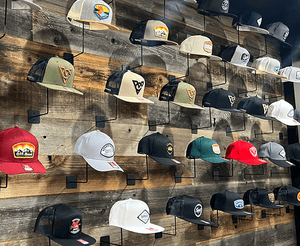 A display of various hats with different designs and colors mounted on a wooden wall.