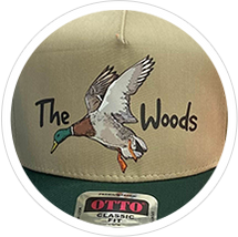 A tan cap featuring a flying duck and the text "The Woods" below it.