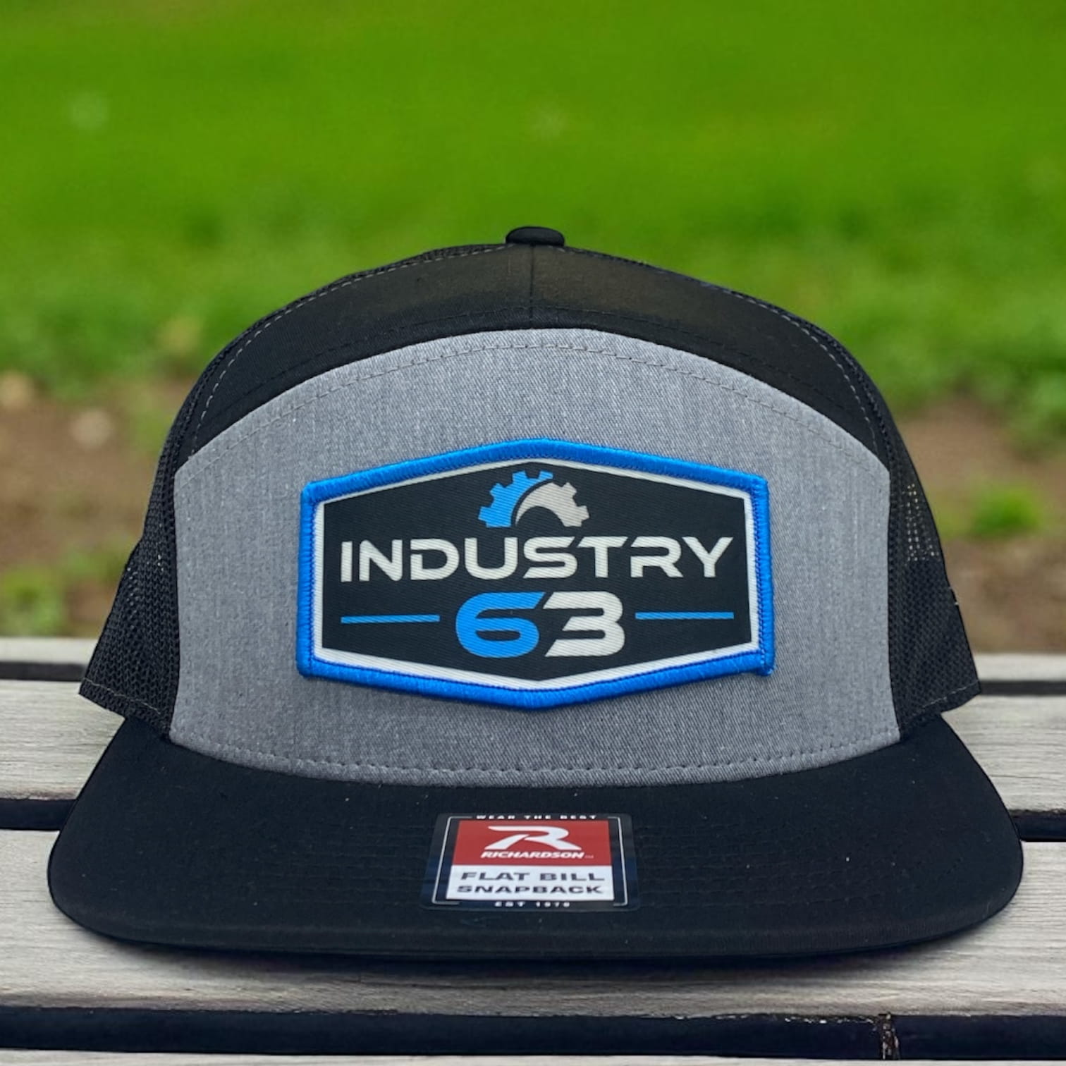 Gray and black Richardson flat bill snapback trucker hat with embroidered Industry 63 patch logo in blue and white.