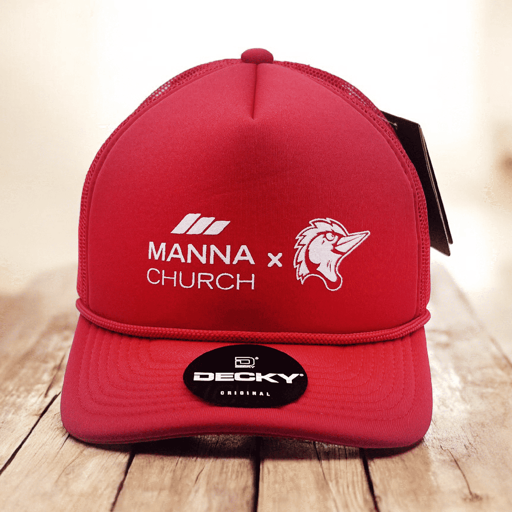 Red Manna Church trucker hat with white logo and rooster icon, product photo on wooden surface.